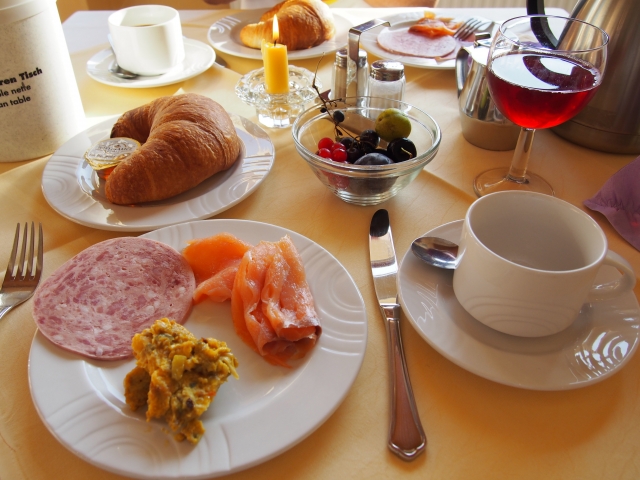 生ハムやサーモン、パン、フルーツ、オリーブが並ぶディナーの写真